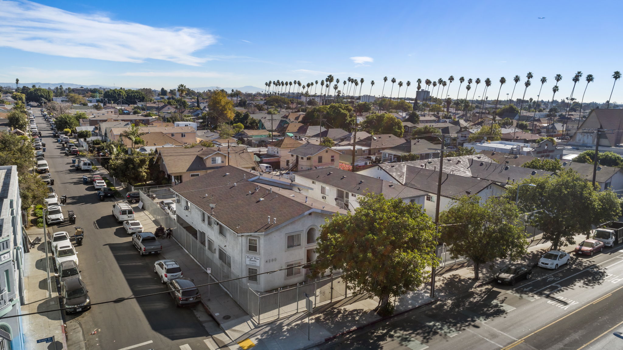A street view of a residential area with houses and parked cars.